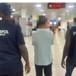 Dai Qisheng (M) being escorted by two INTERPOL operatives at the airport.