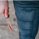 A representational image of a lady with a blood stained knife.