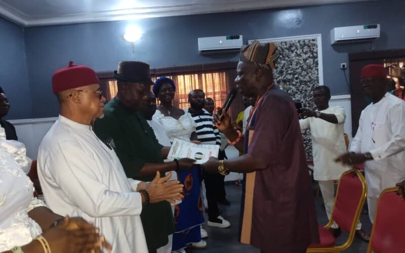 The national chairman, ost Communities of Nigeria (producing oil and gas) (HOSCON), Prince Dr. Mike Emu, presenting a certificate to the Abia State chairman, Hon. Philip Agomuo at the inauguration ceremony.